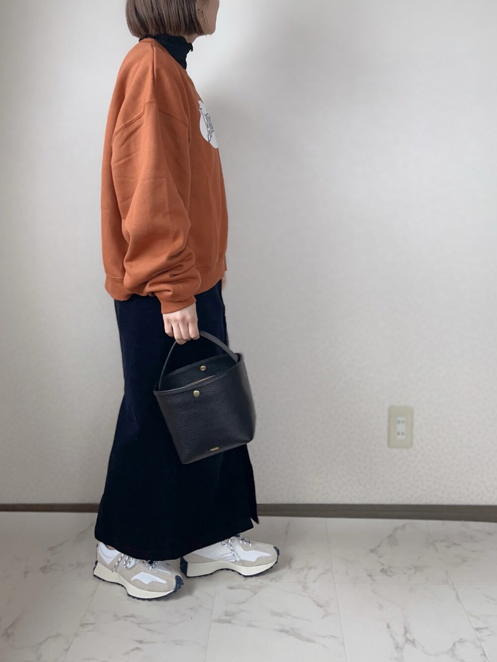 オレンジ系のスウェット、ブラック系のTシャツ/カットソー、ブルー系のスカートを着用したレディースの冬コーディネートの2枚目の写真