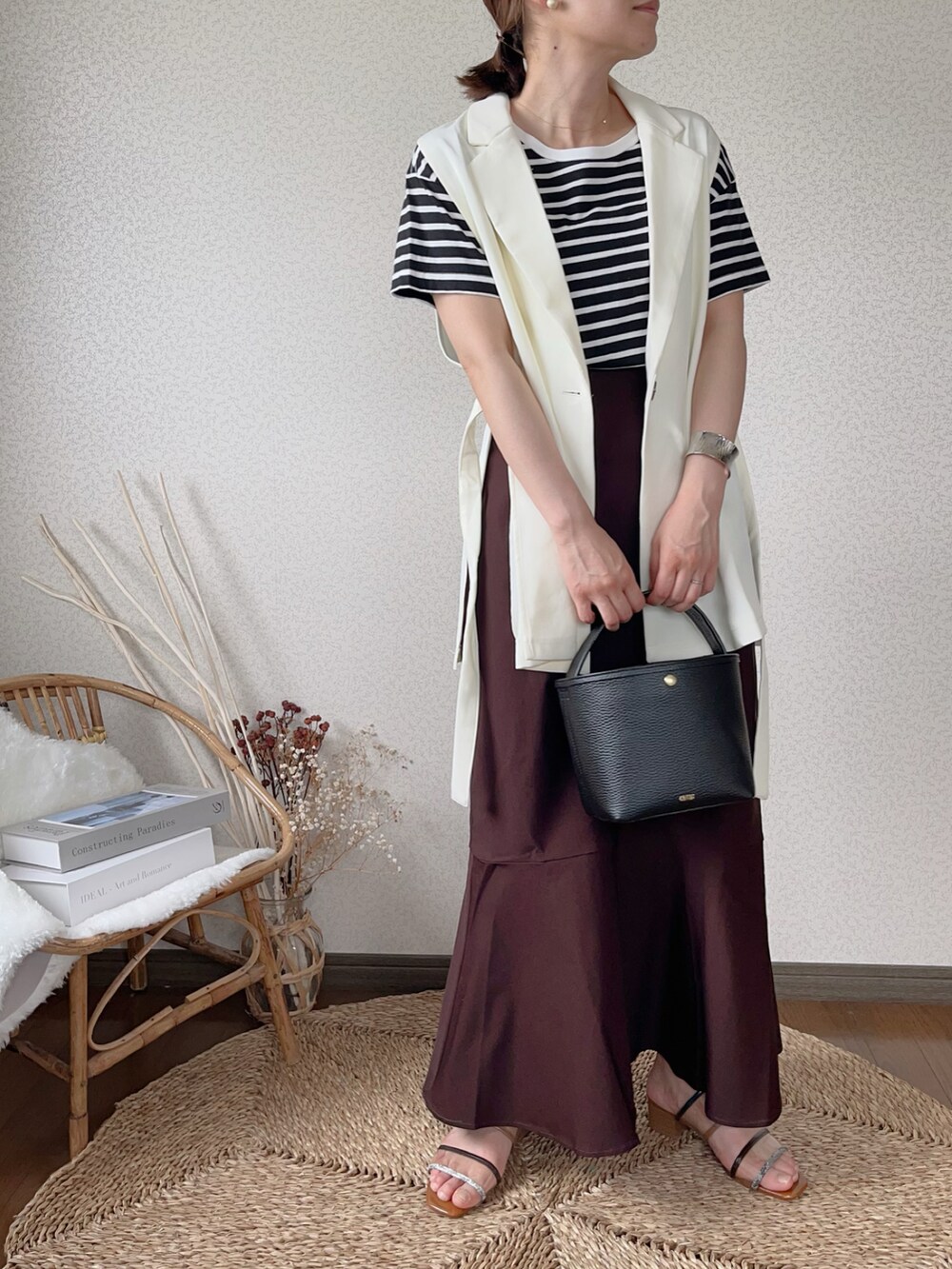 ブラウン系のスカート、ホワイト系のベストを着用したレディースの夏コーディネートの2枚目の写真