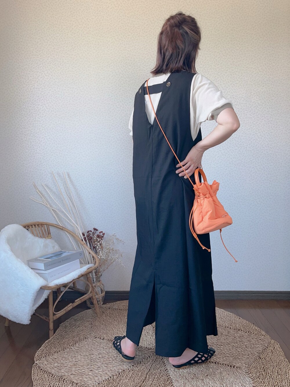 ベージュ系のニット/セーター、ブラック系のワンピース、オレンジ系のハンドバッグを着用したレディースの夏コーディネートの2枚目の写真