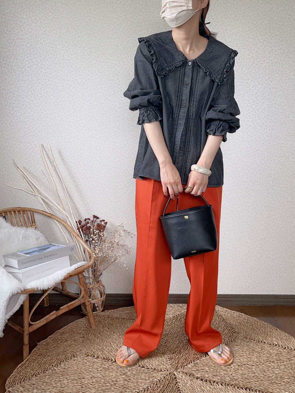 ブラック系のシャツ/ブラウス、オレンジ系のスラックス、ゴールド系のピアス（両耳用）を着用したレディースの夏コーディネートの2枚目の写真