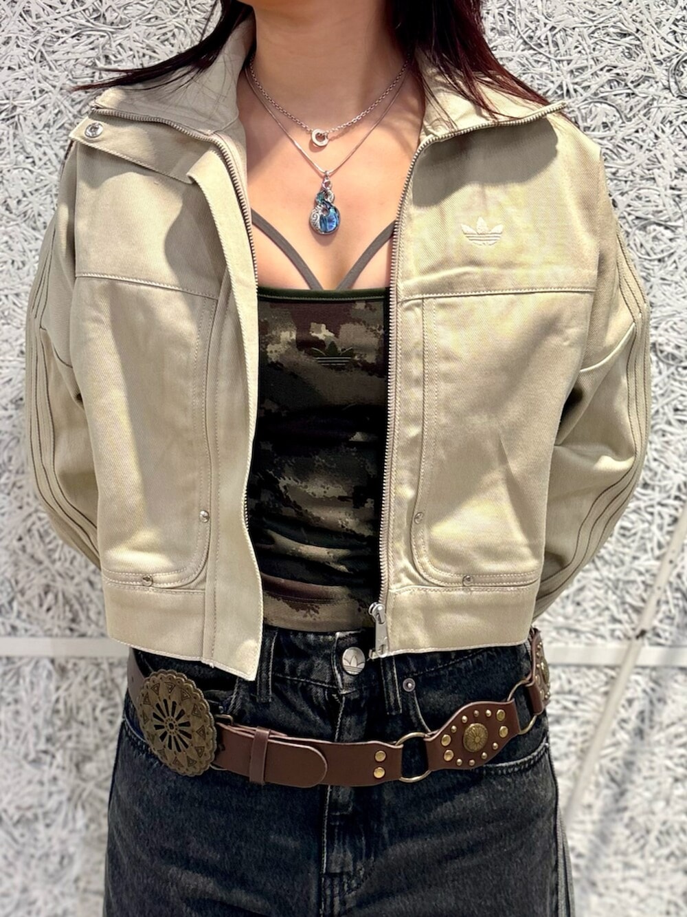 グリーン系のデニムジャケット、ブラック系のデニムパンツ、ホワイト系のスニーカーを着用したレディースの夏コーディネートの3枚目の写真