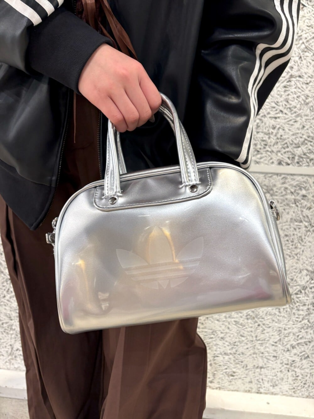 ブラック系のブルゾン、ベージュ系のスニーカー、シルバー系のショルダーバッグを着用したレディースの春コーディネートの3枚目の写真