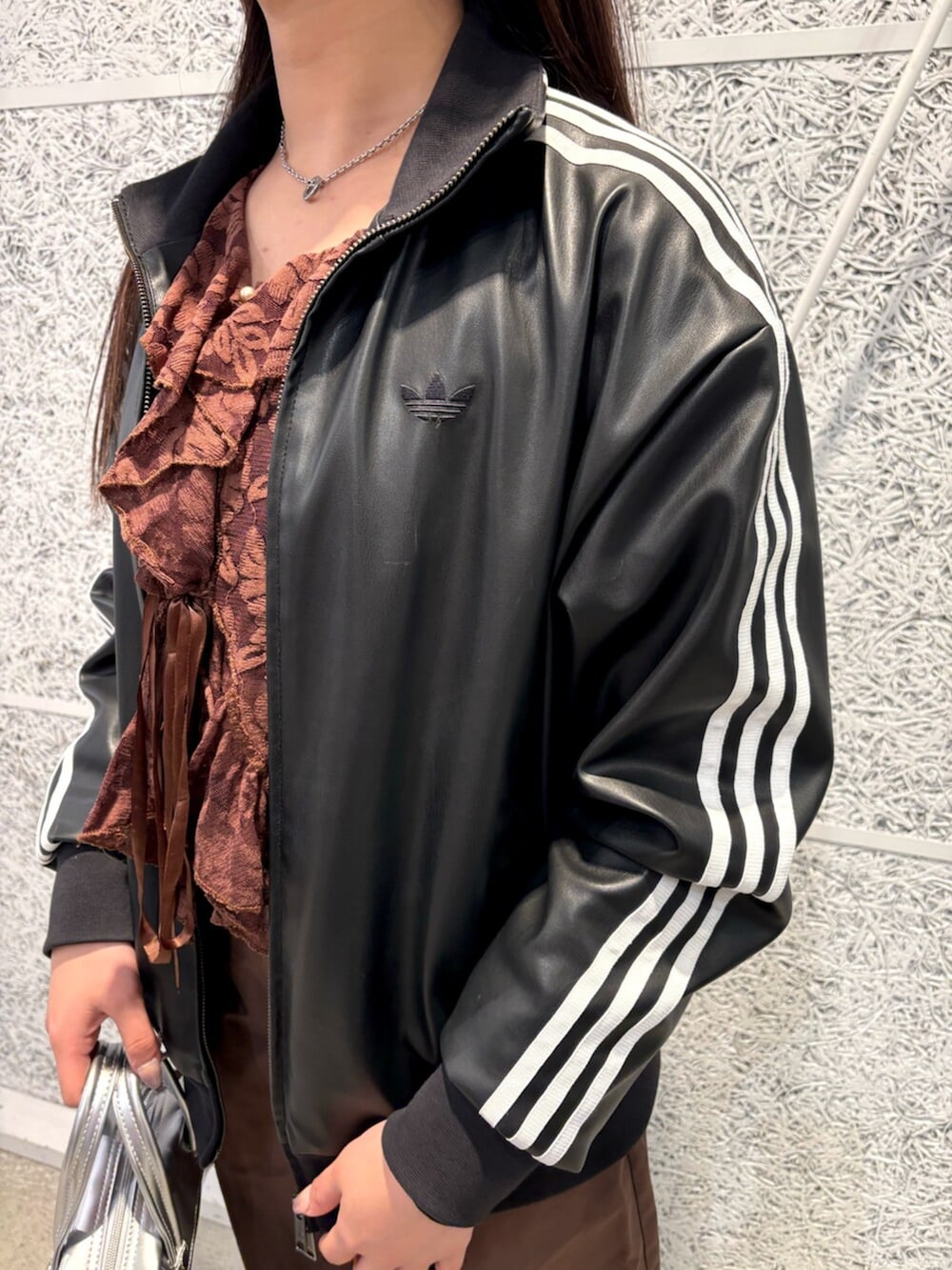 ブラック系のブルゾン、ベージュ系のスニーカー、シルバー系のショルダーバッグを着用したレディースの春コーディネートの2枚目の写真