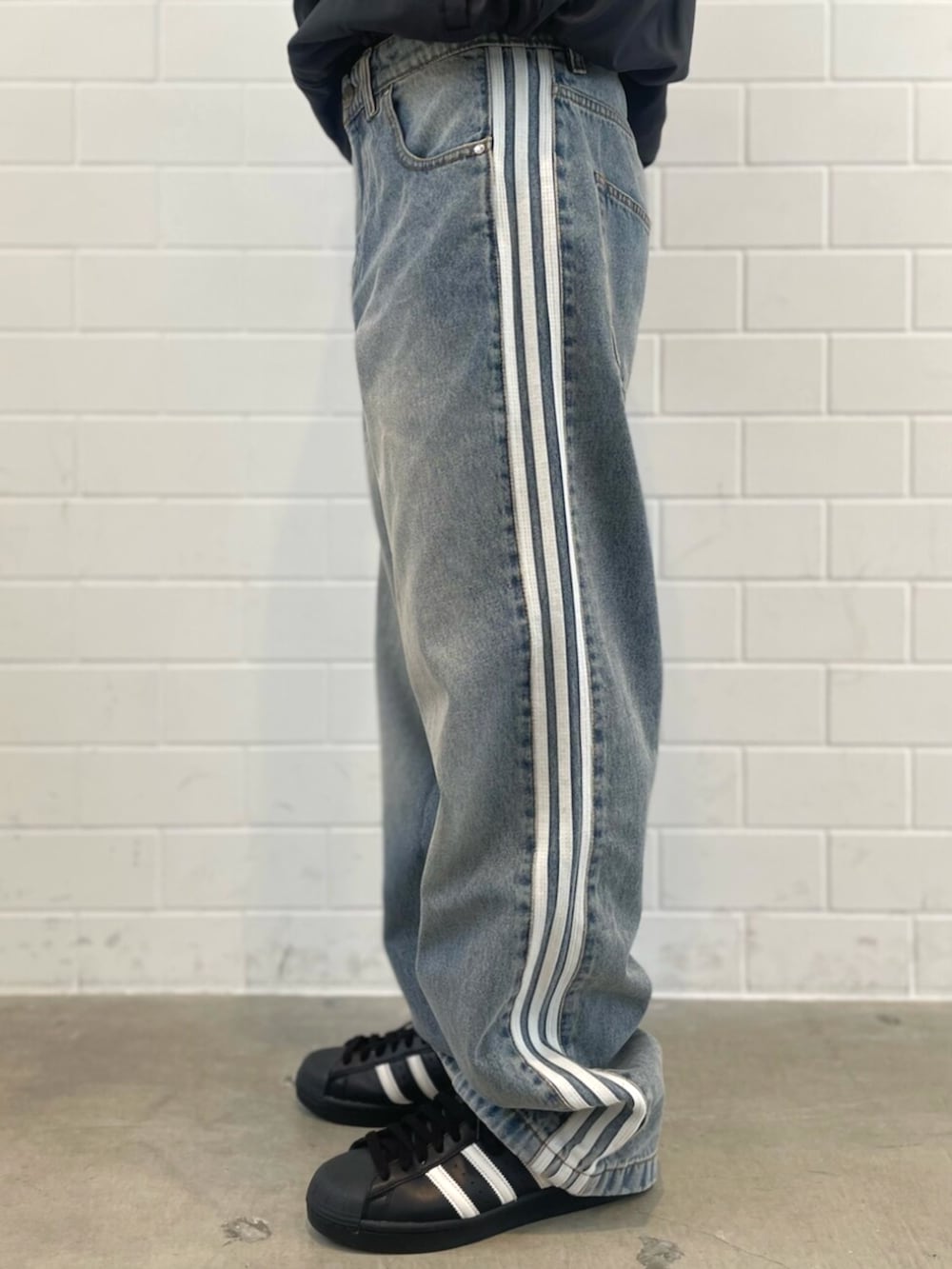 ブラック系のシューズ、ブラック系のジャージ、ブルー系のデニムパンツを着用したメンズの春コーディネートの5枚目の写真