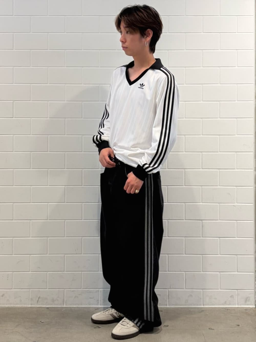 ブラック系のデニムパンツ、ホワイト系のトップス、ホワイト系のスニーカーを着用したメンズの春コーディネートの3枚目の写真