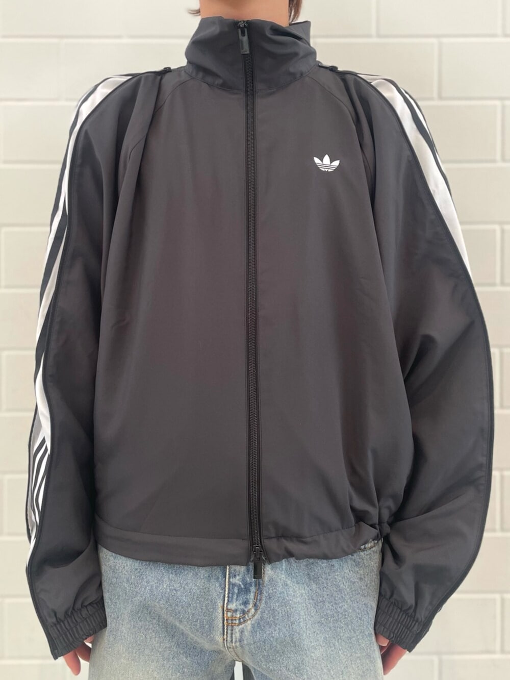 ブラック系のシューズ、ブラック系のジャージ、ブルー系のデニムパンツを着用したメンズの春コーディネートの3枚目の写真