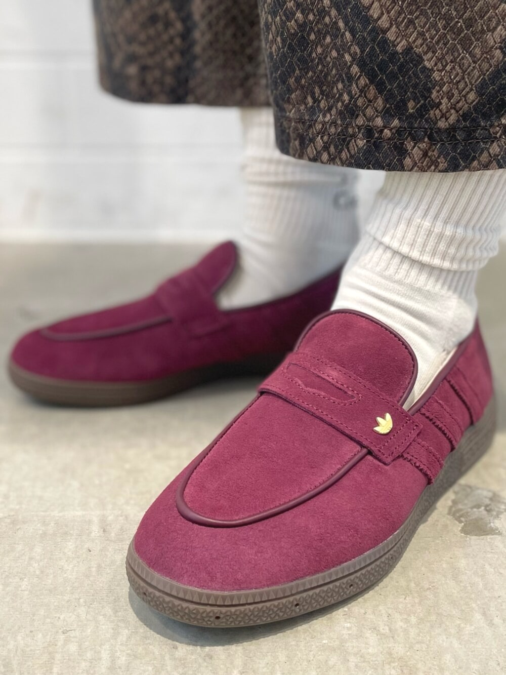 レッド系のスニーカー、グレー系のジャージ、ブラウン系のデニムパンツを着用したメンズの夏コーディネートの6枚目の写真