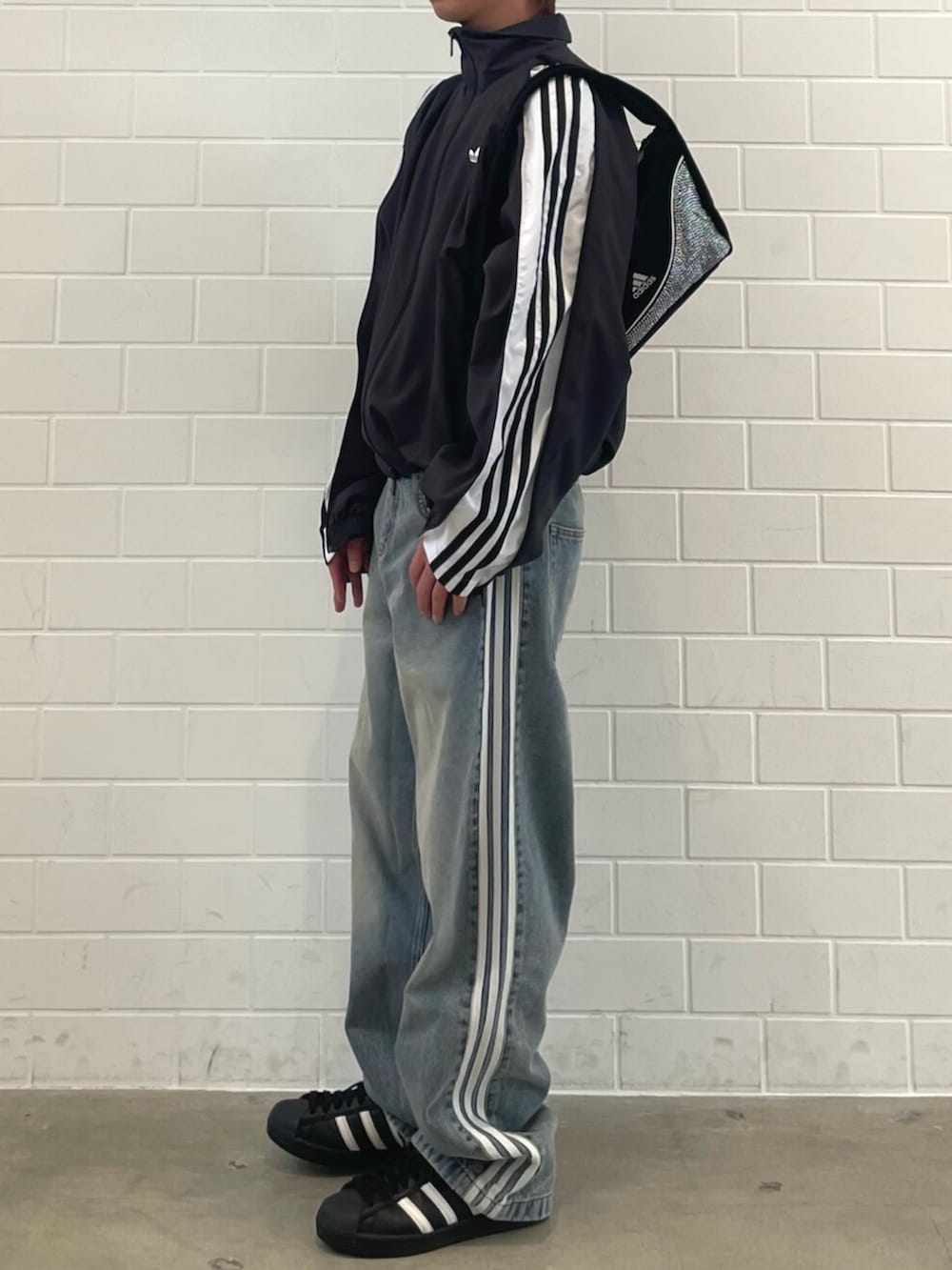 ブラック系のシューズ、ブラック系のジャージ、ブルー系のデニムパンツを着用したメンズの春コーディネートの2枚目の写真