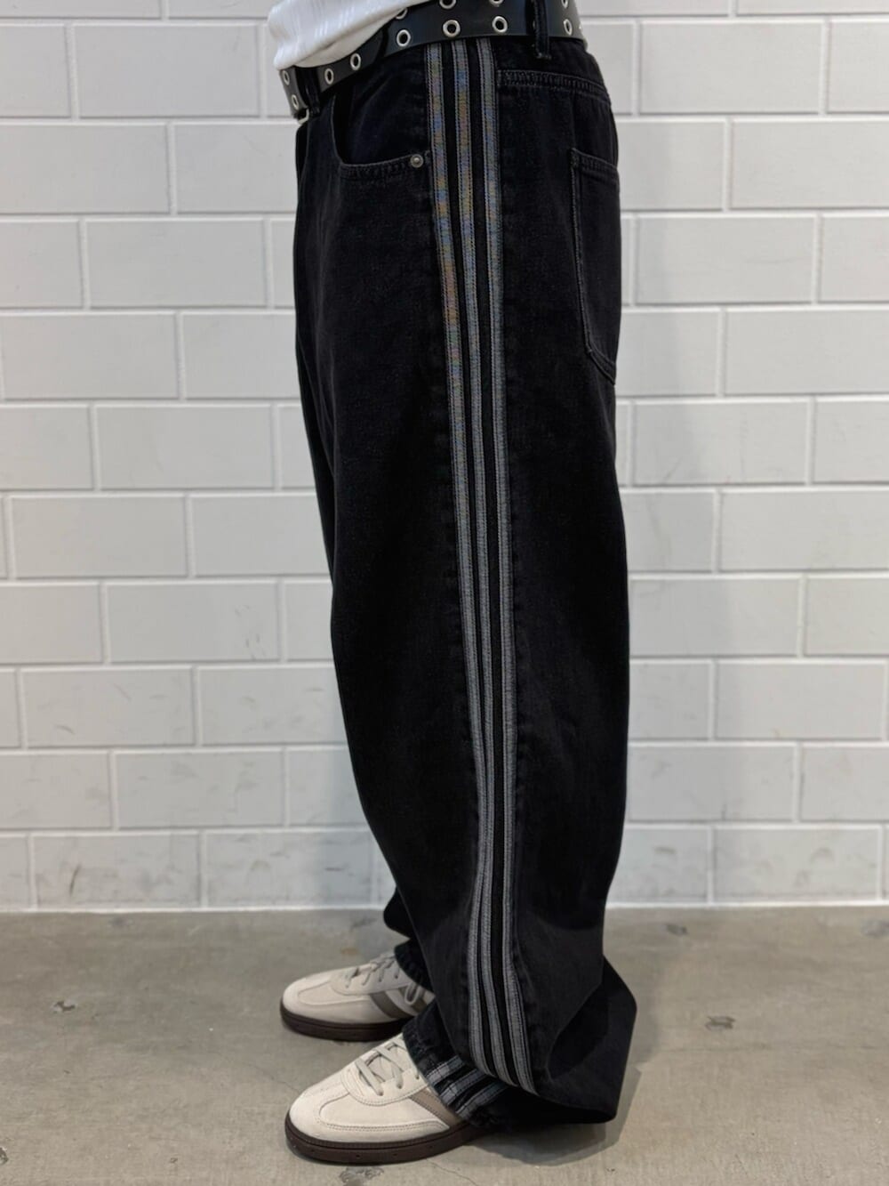 ブラック系のデニムパンツ、ホワイト系のトップス、ホワイト系のスニーカーを着用したメンズの春コーディネートの5枚目の写真