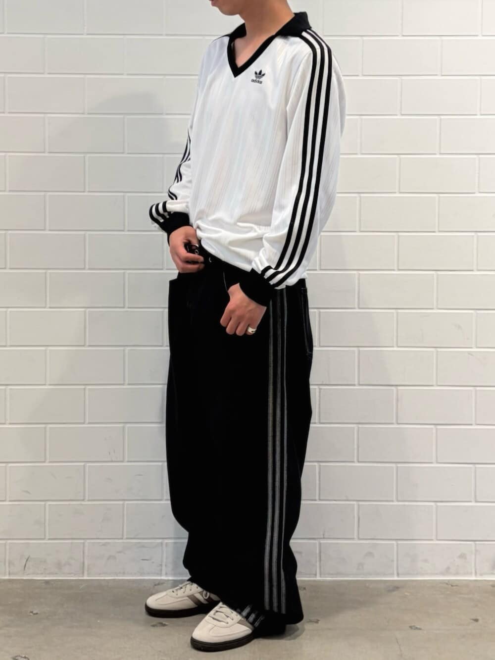 ブラック系のデニムパンツ、ホワイト系のトップス、ホワイト系のスニーカーを着用したメンズの春コーディネートの2枚目の写真