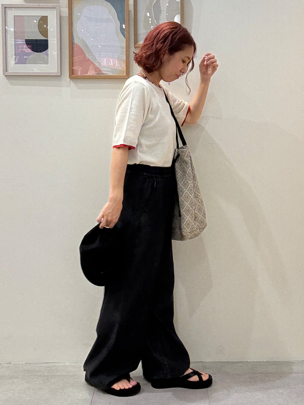 ホワイト系のニット/セーター、ブラック系のデニムパンツ、ベージュ系のトートバッグを着用したレディースの夏コーディネートの2枚目の写真