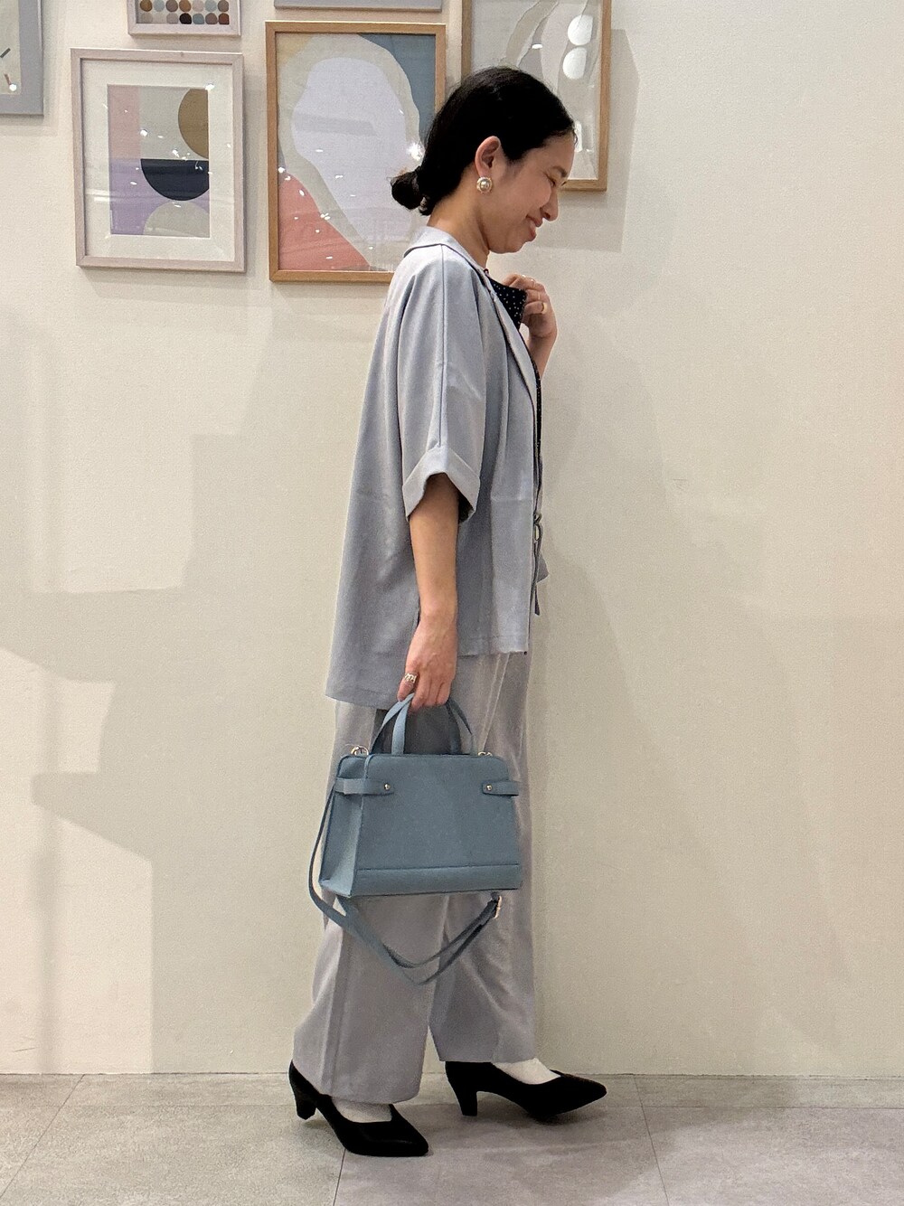 ブラック系のパンプス、ブルー系のシャツ/ブラウス、ブルー系のショルダーバッグを着用したレディースの春コーディネートの2枚目の写真