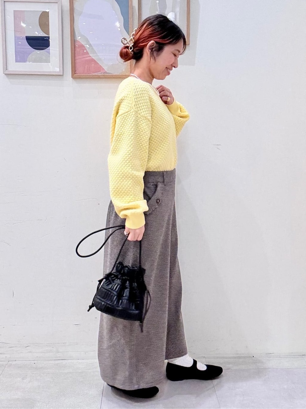 イエロー系のニット/セーター、ブラウン系のその他パンツ、ブラック系のショルダーバッグを着用したレディースの冬コーディネートの2枚目の写真
