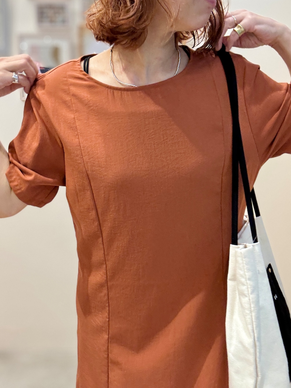 オレンジ系のワンピース、ホワイト系のトートバッグ、ブラック系のサンダルを着用したレディースの夏コーディネートの4枚目の写真