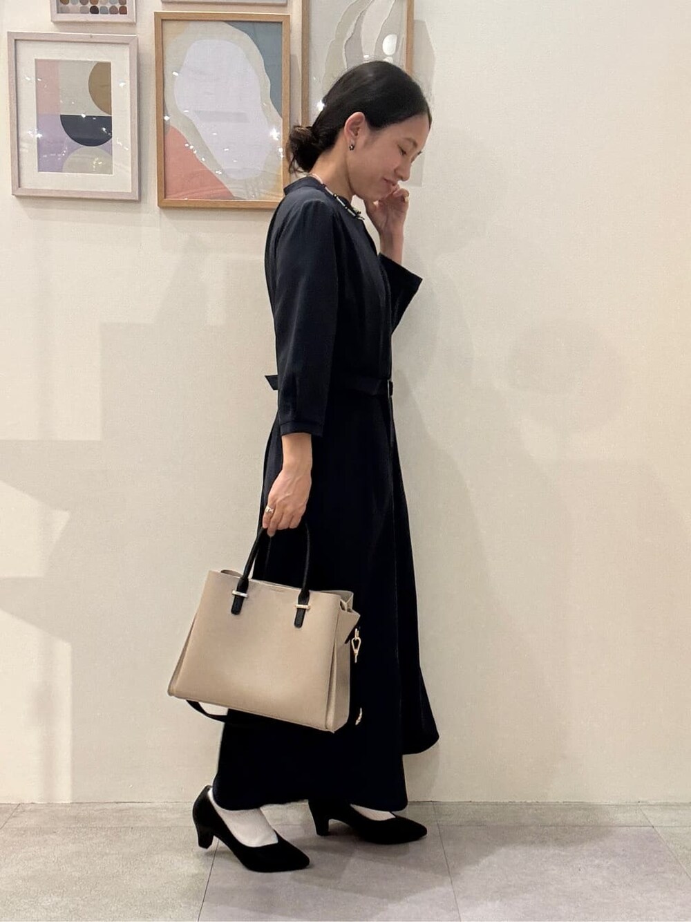 ブラック系のパンプス、ベージュ系のトートバッグ、ブルー系のワンピースを着用したレディースの春コーディネートの2枚目の写真