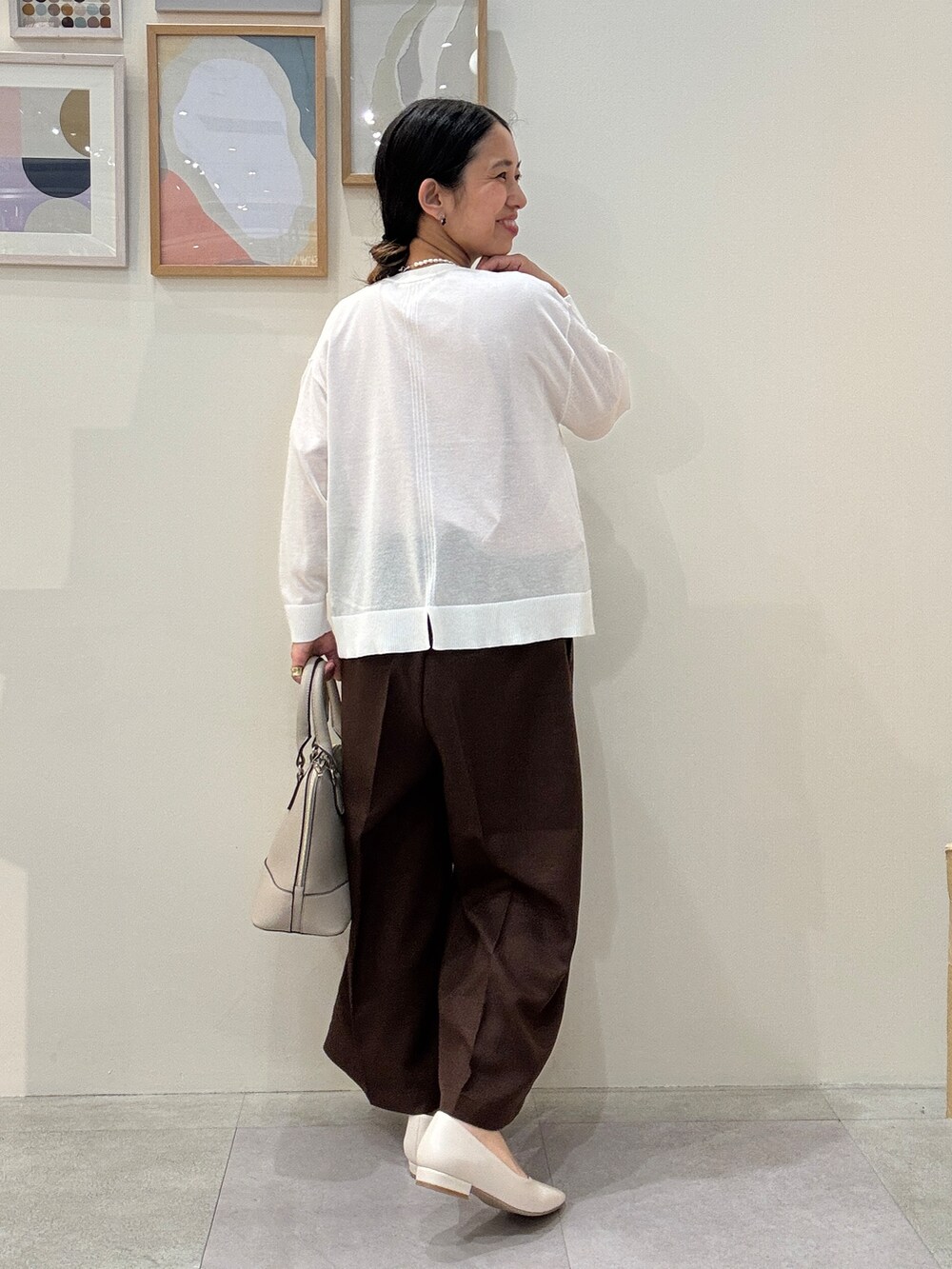 グレー系のトートバッグ、ホワイト系のパンプス、ホワイト系のカーディガン/ボレロを着用したレディースの春コーディネートの3枚目の写真