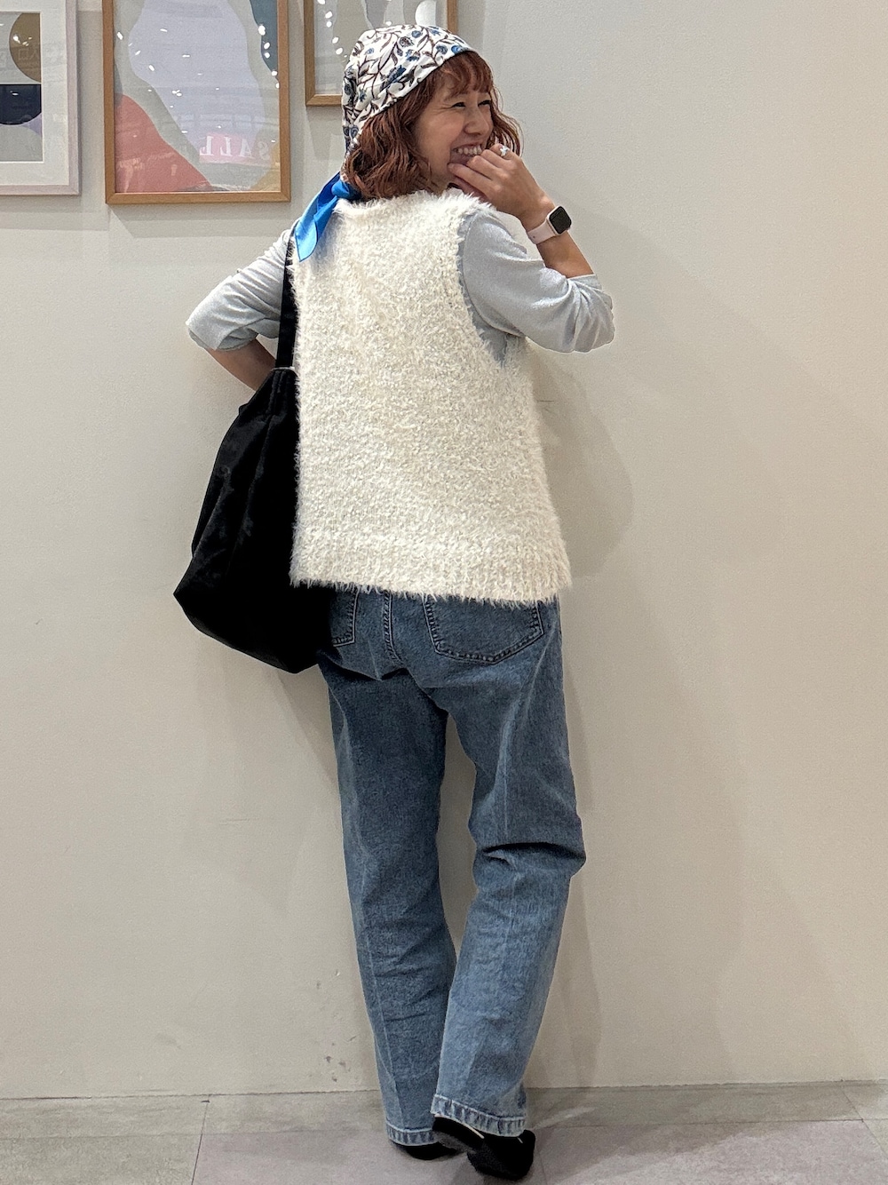 ホワイト系のベスト、ブルー系のデニムパンツ、ブラック系のショルダーバッグを着用したレディースの秋コーディネートの3枚目の写真