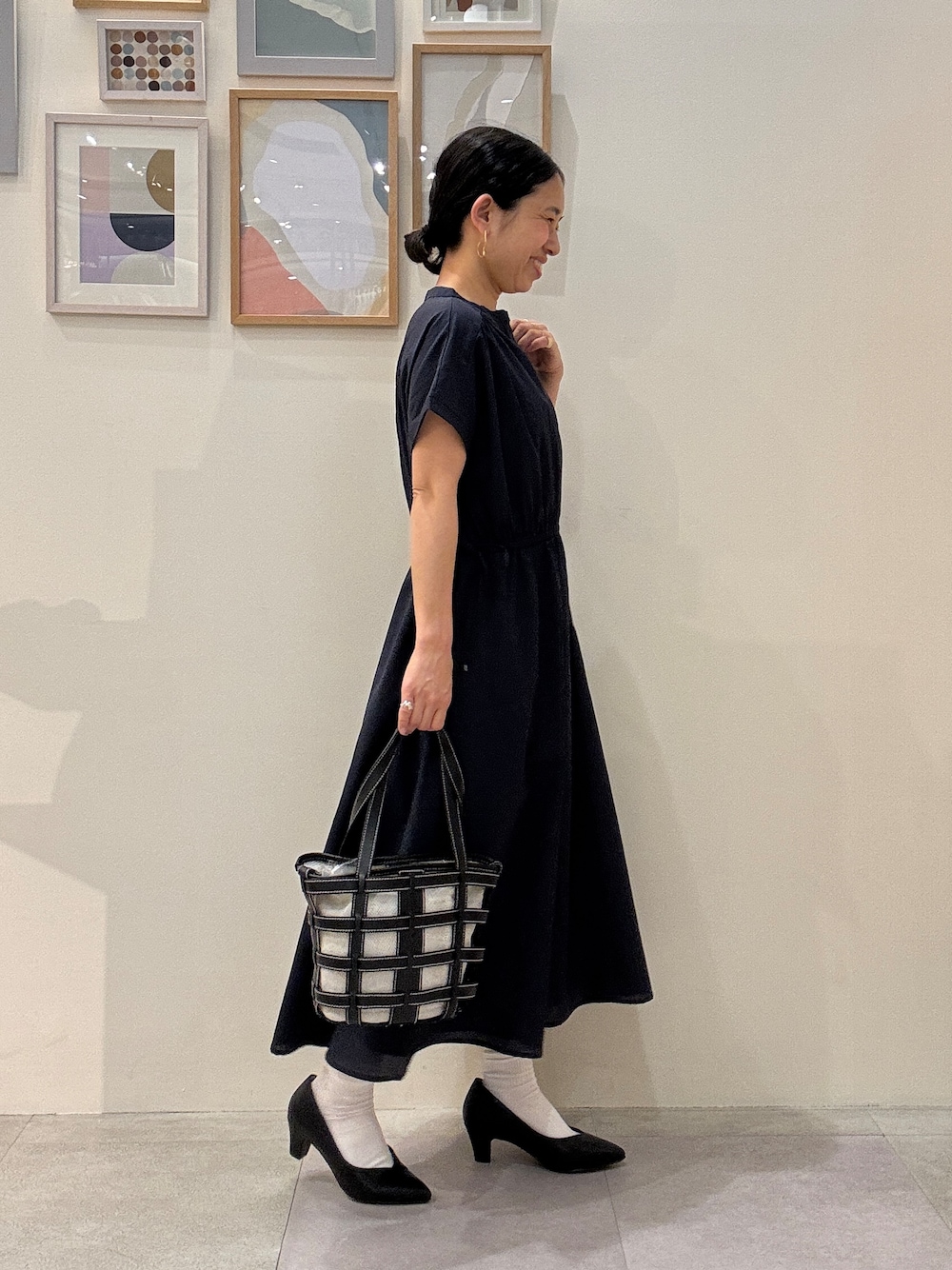 ブラック系のパンプス、ブラック系のトートバッグ、ブルー系のワンピースを着用したレディースの春コーディネートの2枚目の写真