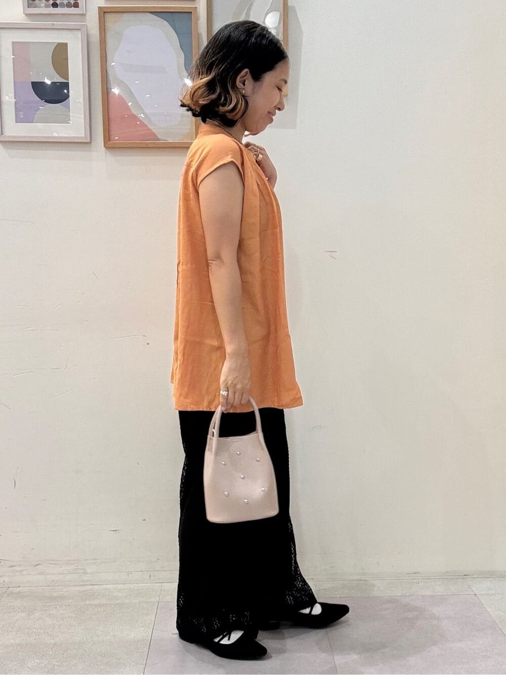オレンジ系のシャツ/ブラウス、ブラック系のその他パンツ、ベージュ系のショルダーバッグを着用したレディースの夏コーディネートの2枚目の写真