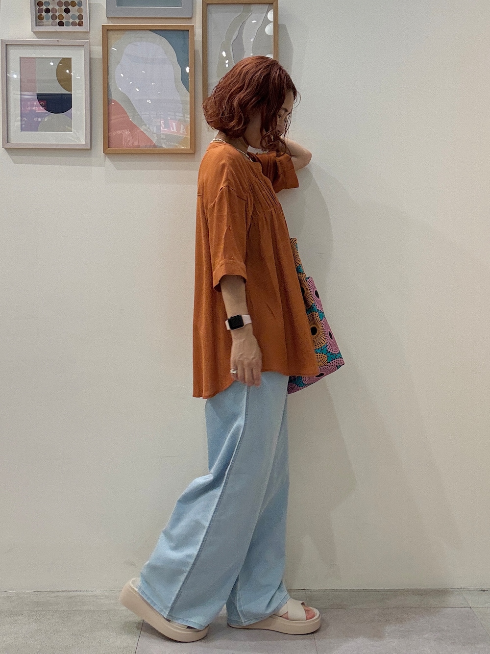 オレンジ系のシャツ/ブラウス、ブルー系のデニムパンツ、ブルー系のトートバッグを着用したレディースの夏コーディネートの2枚目の写真
