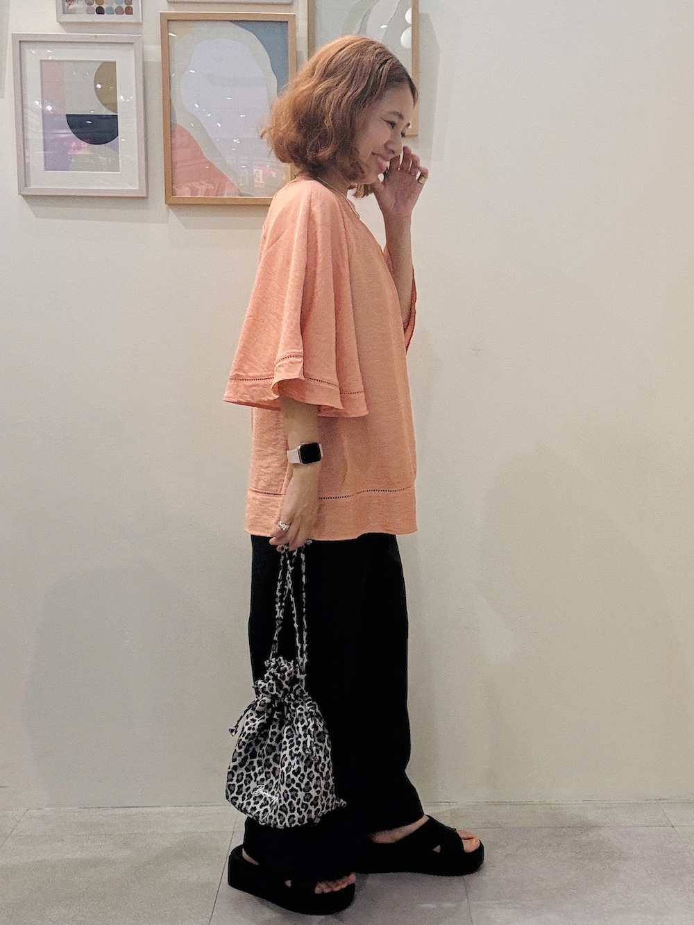 オレンジ系のシャツ/ブラウス、グレー系のその他パンツ、ベージュ系のショルダーバッグを着用したレディースの夏コーディネートの2枚目の写真