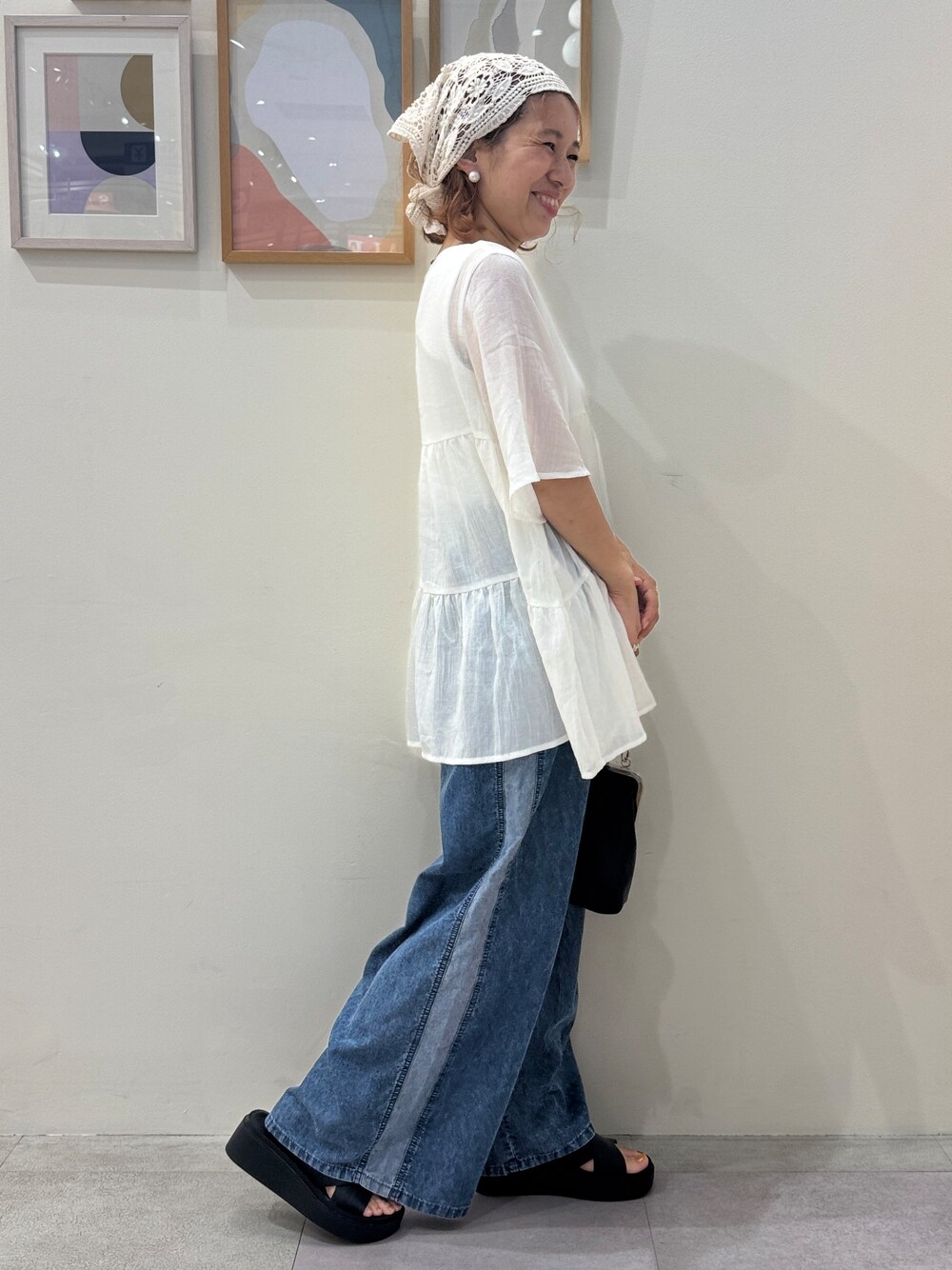 ブルー系のデニムパンツ、ブラック系のサンダルを着用したレディースの夏コーディネートの2枚目の写真