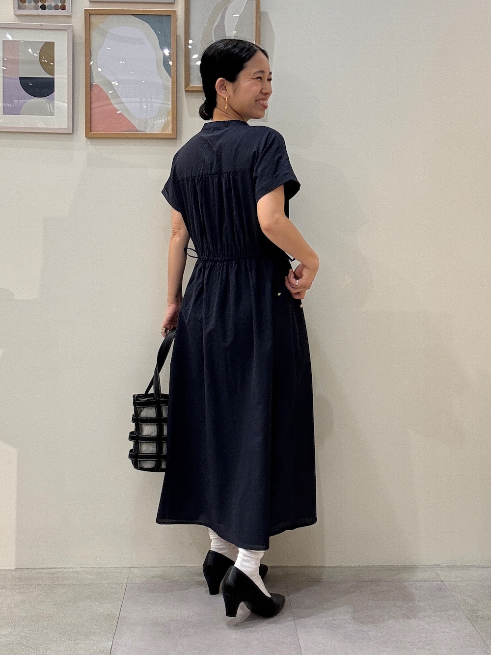 ブラック系のパンプス、ブラック系のトートバッグ、ブルー系のワンピースを着用したレディースの春コーディネートの3枚目の写真