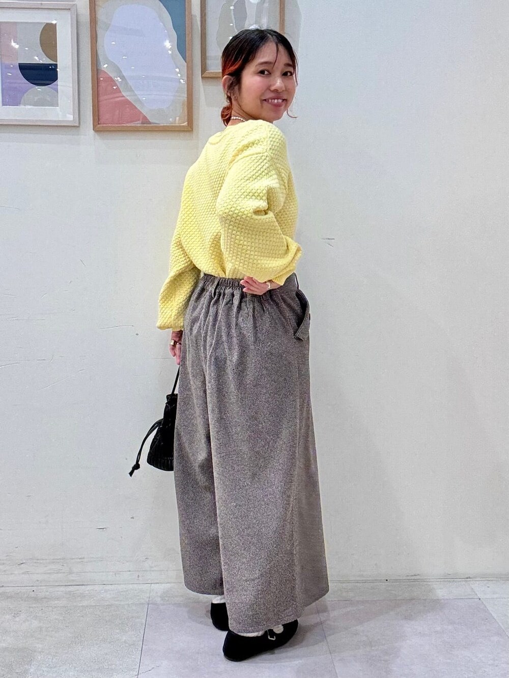 イエロー系のニット/セーター、ブラウン系のその他パンツ、ブラック系のショルダーバッグを着用したレディースの冬コーディネートの3枚目の写真
