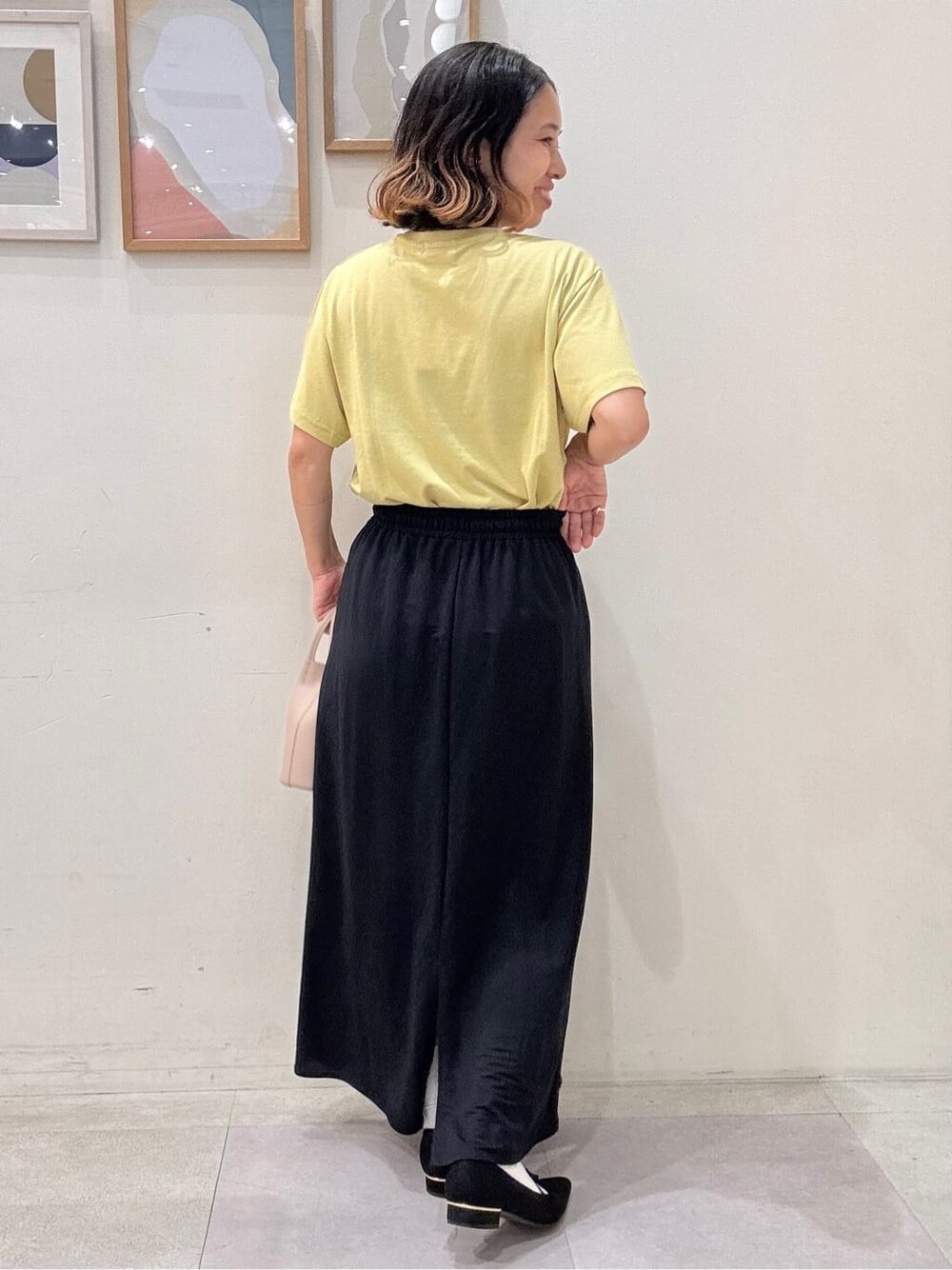 イエロー系のTシャツ/カットソー、ブルー系のスカート、ベージュ系のショルダーバッグを着用したレディースの夏コーディネートの3枚目の写真