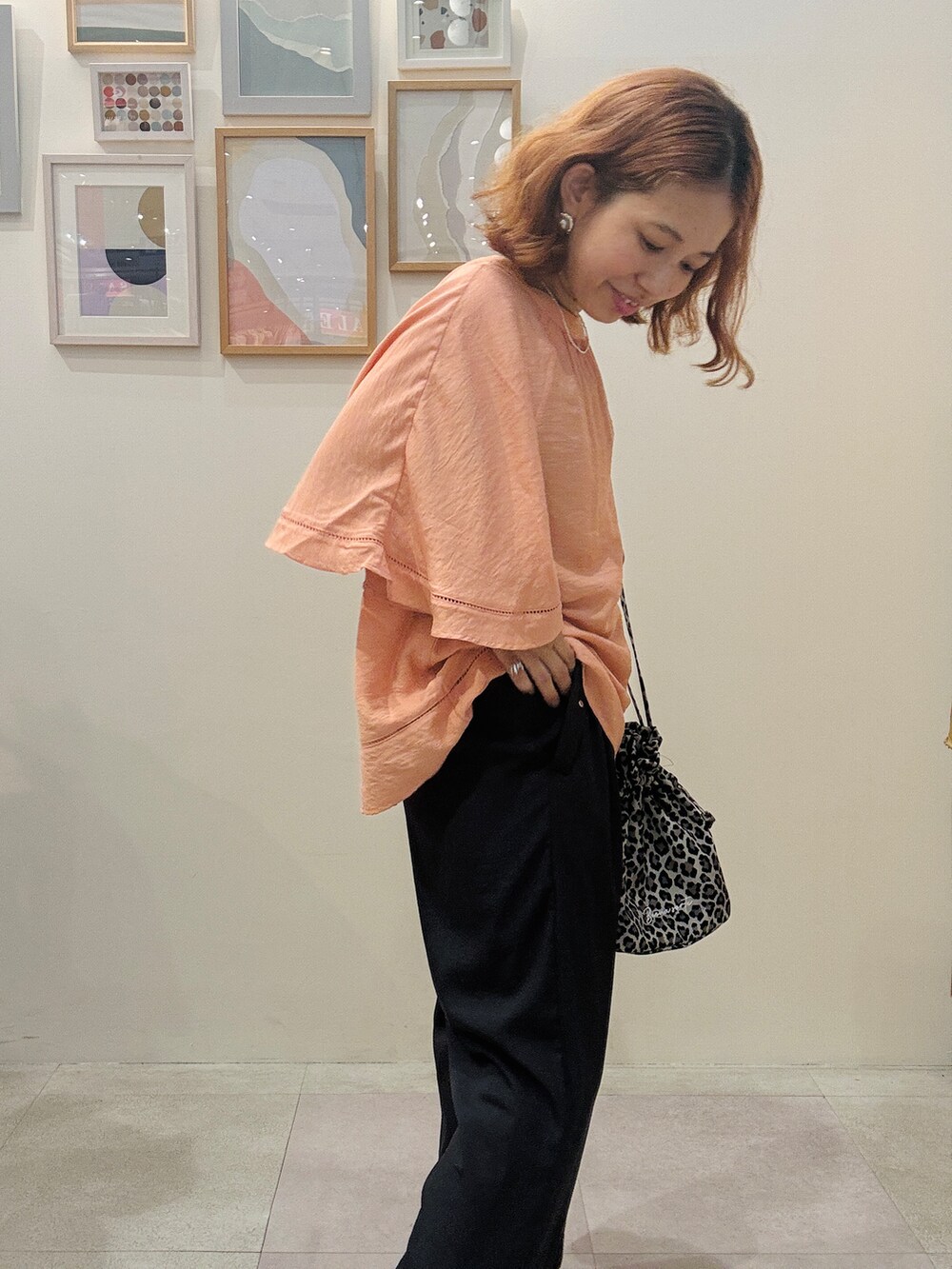 オレンジ系のシャツ/ブラウス、グレー系のその他パンツ、ベージュ系のショルダーバッグを着用したレディースの夏コーディネートの4枚目の写真