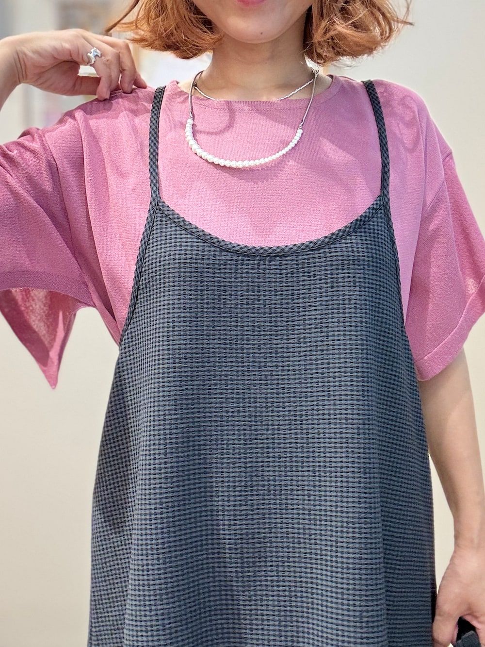 ピンク系のニット/セーター、グレー系のワンピース、ブラック系のショルダーバッグを着用したレディースの夏コーディネートの5枚目の写真