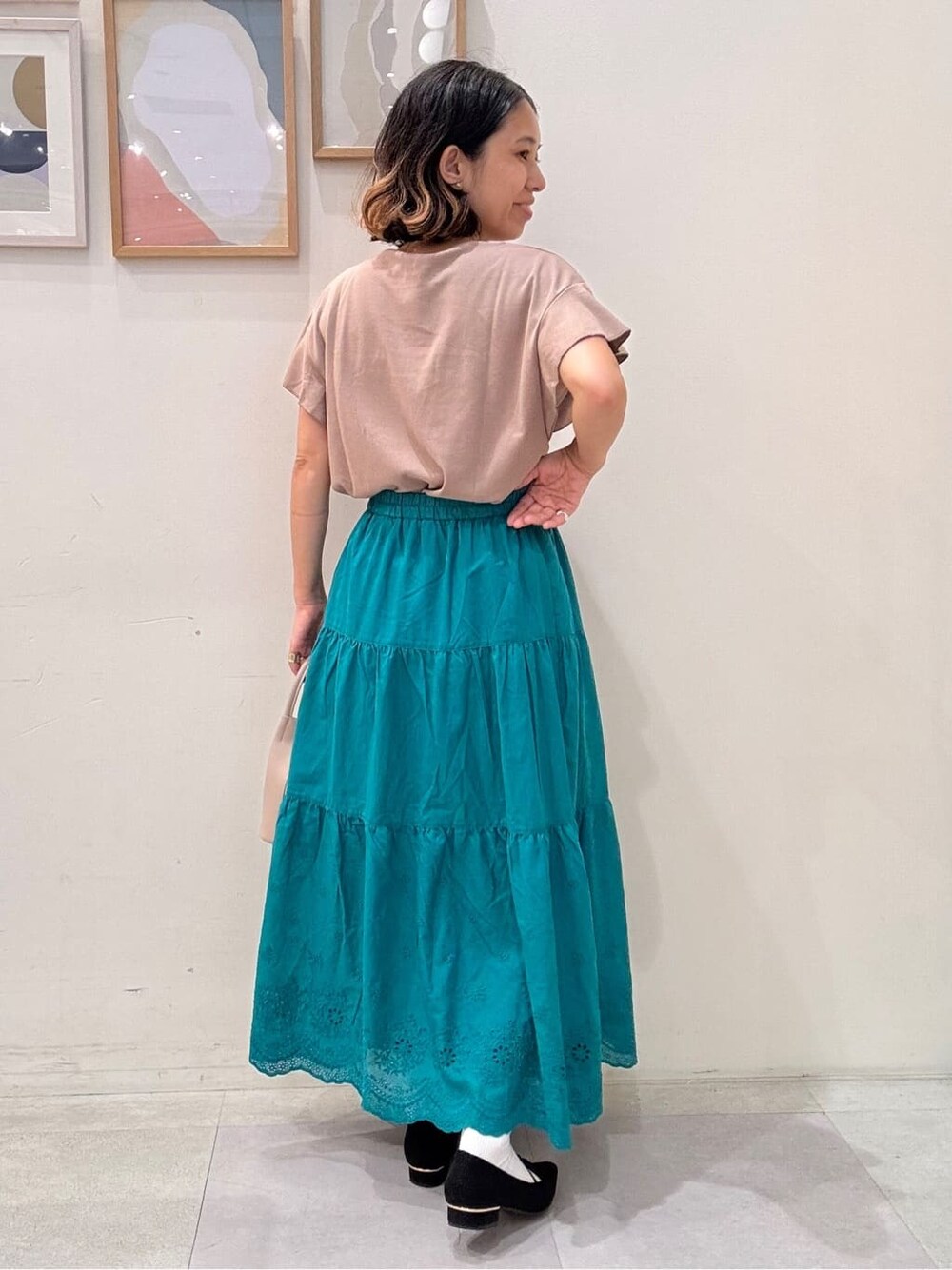 ブラウン系のTシャツ/カットソー、グリーン系のスカート、ベージュ系のショルダーバッグを着用したレディースの秋コーディネートの3枚目の写真