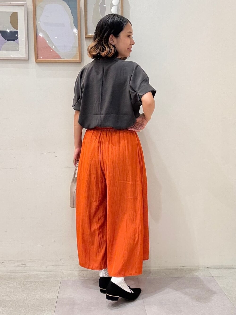 グレー系のシャツ/ブラウス、オレンジ系のその他パンツ、ベージュ系のショルダーバッグを着用したレディースの夏コーディネートの3枚目の写真