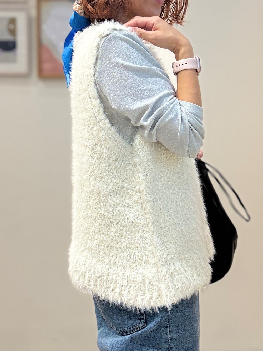 ホワイト系のベスト、ブルー系のデニムパンツ、ブラック系のショルダーバッグを着用したレディースの秋コーディネートの4枚目の写真