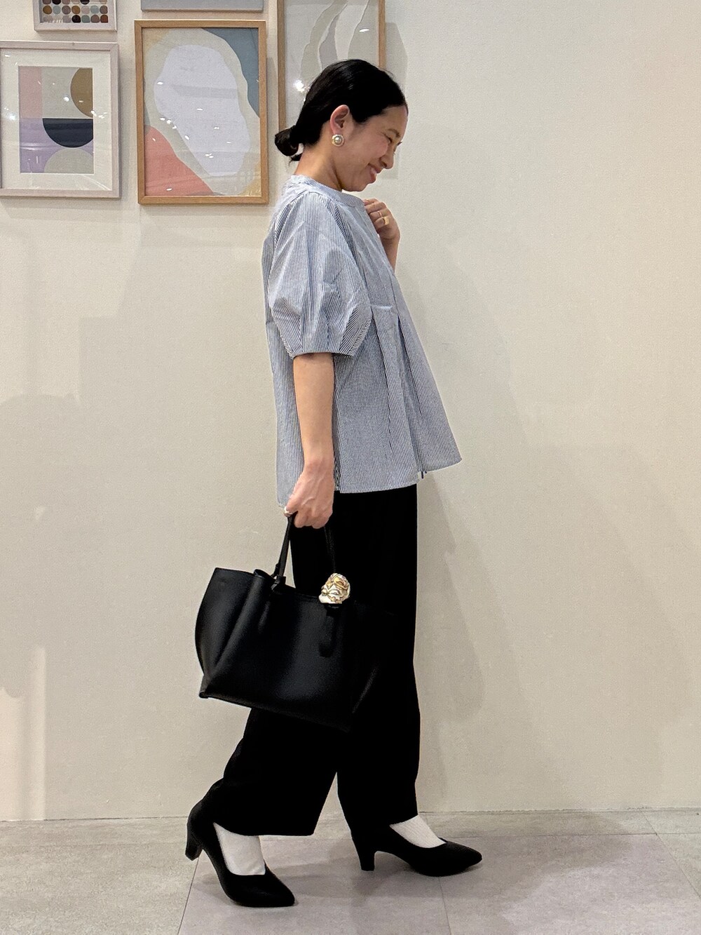 ブラック系のパンプス、ブルー系のシャツ/ブラウス、ブラック系のトートバッグを着用したレディースの春コーディネートの2枚目の写真
