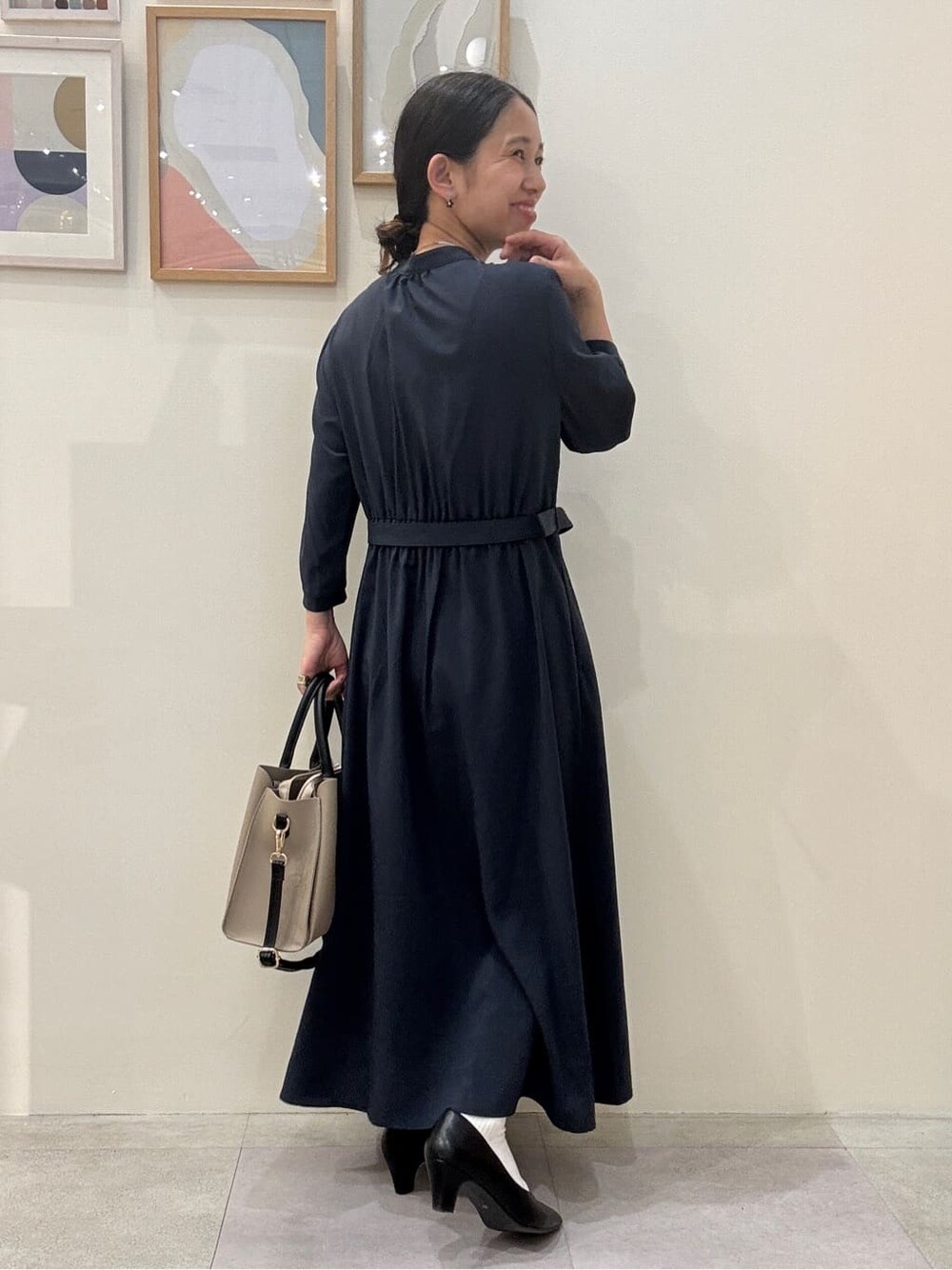 ブラック系のパンプス、ベージュ系のトートバッグ、ブルー系のワンピースを着用したレディースの春コーディネートの3枚目の写真