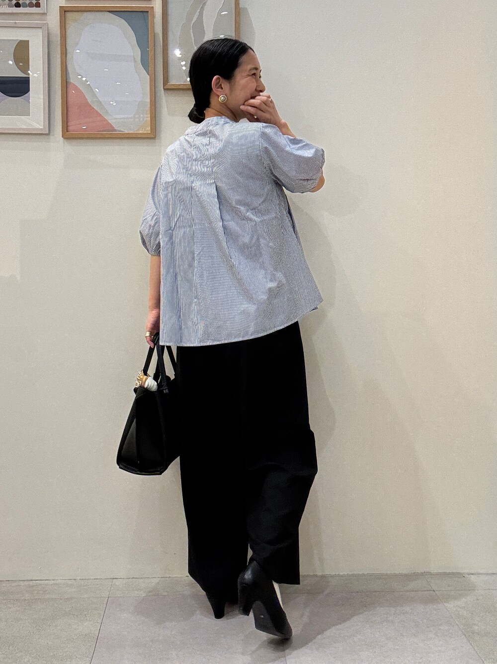 ブラック系のパンプス、ブルー系のシャツ/ブラウス、ブラック系のトートバッグを着用したレディースの春コーディネートの3枚目の写真