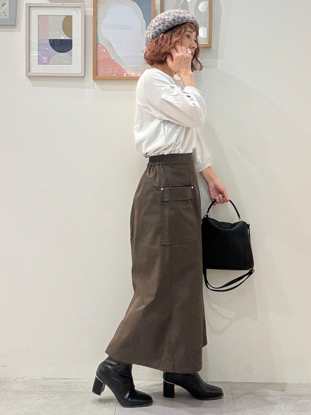 グレー系のTシャツ/カットソー、ブラウン系のスカート、ブラック系のブーツを着用したレディースの秋コーディネートの2枚目の写真