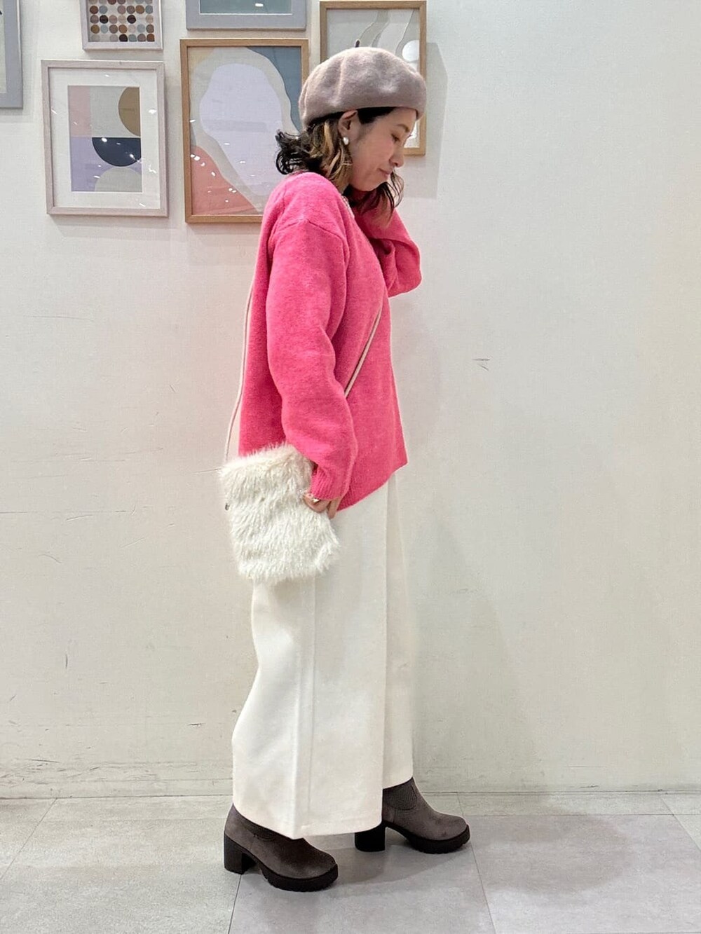 ピンク系のニット/セーター、ホワイト系のその他パンツ、ブラウン系のブーツを着用したレディースの冬コーディネートの2枚目の写真