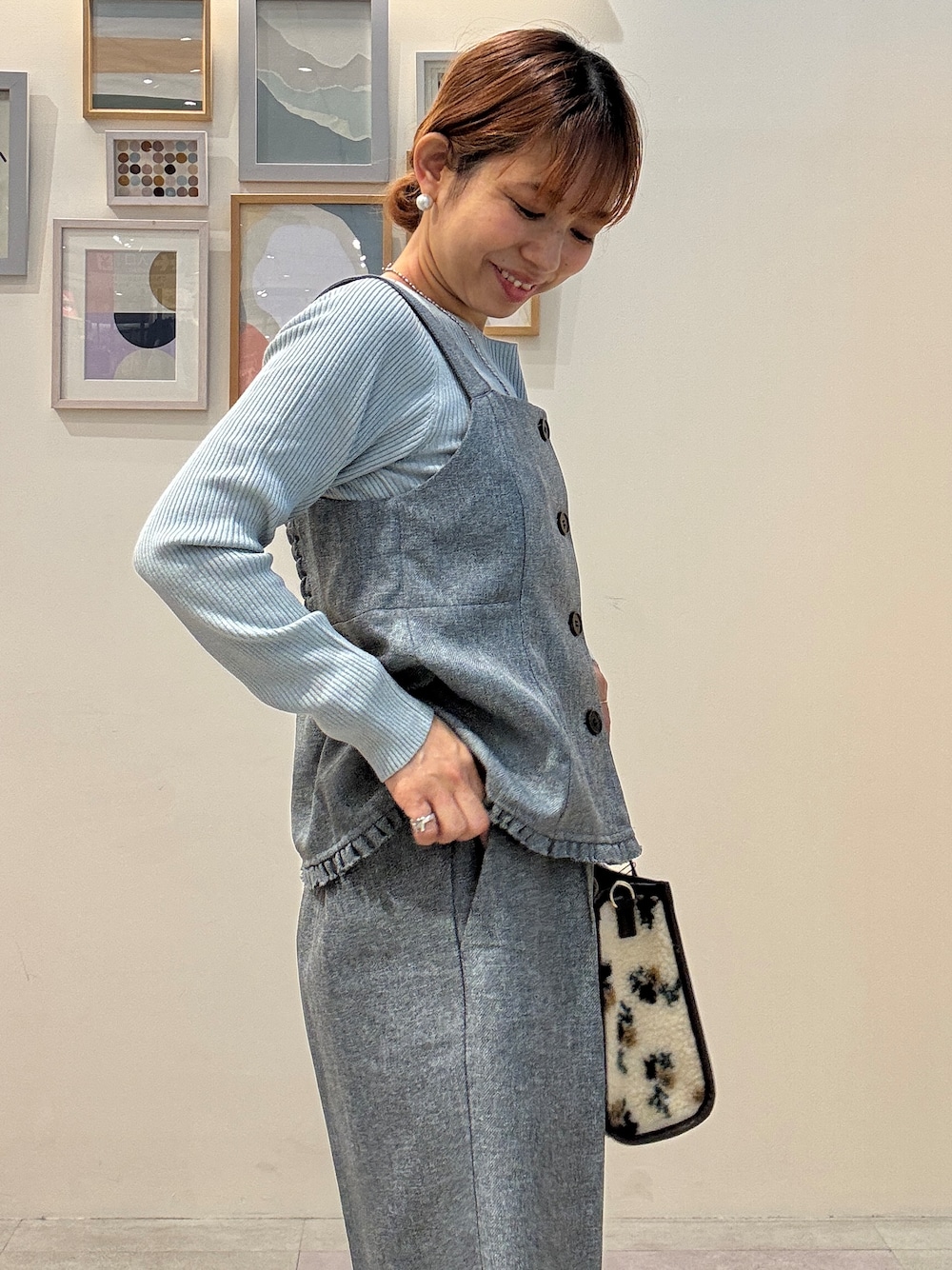 ブルー系のニット/セーター、ブラウン系のトートバッグ、シルバー系のネックレスを着用したレディースの秋コーディネートの4枚目の写真
