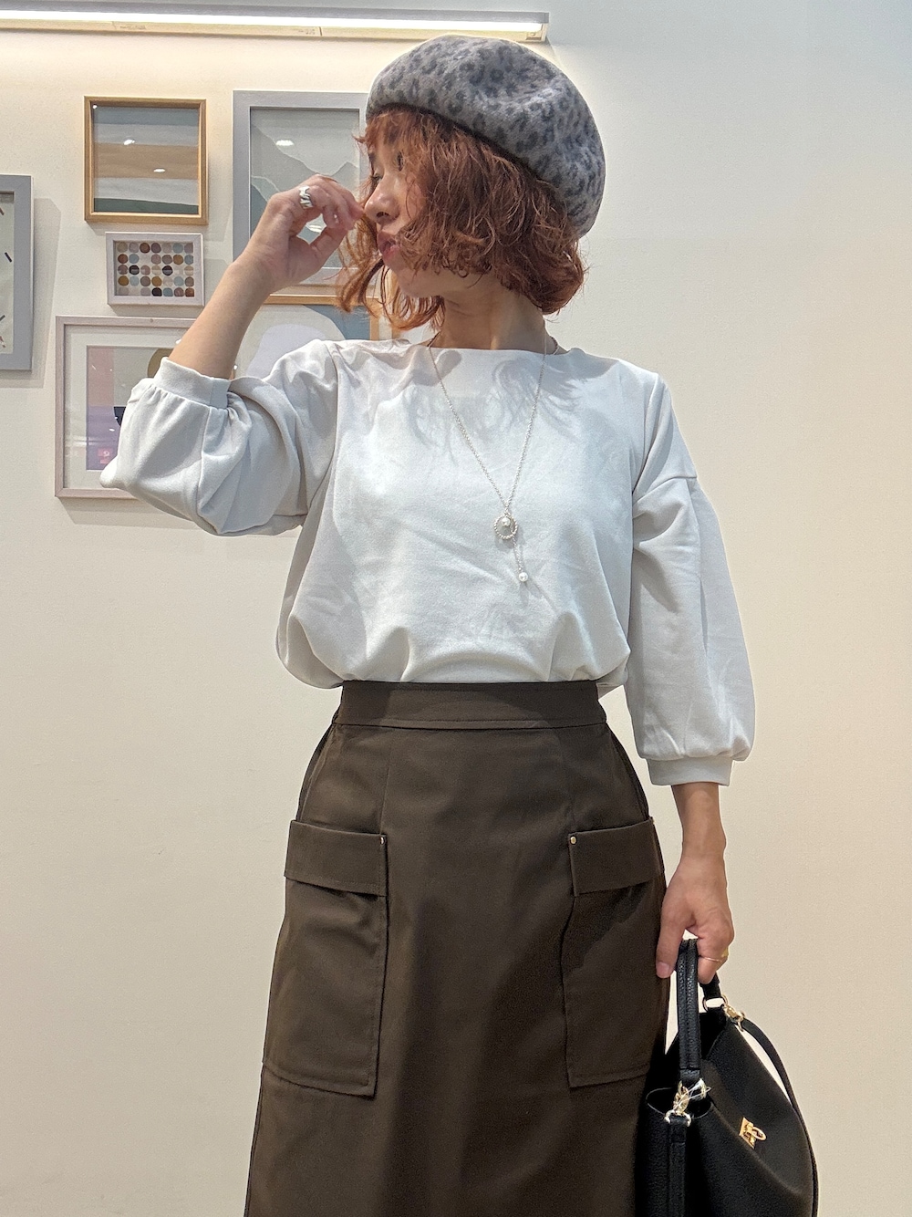 グレー系のTシャツ/カットソー、ブラウン系のスカート、ブラック系のブーツを着用したレディースの秋コーディネートの4枚目の写真