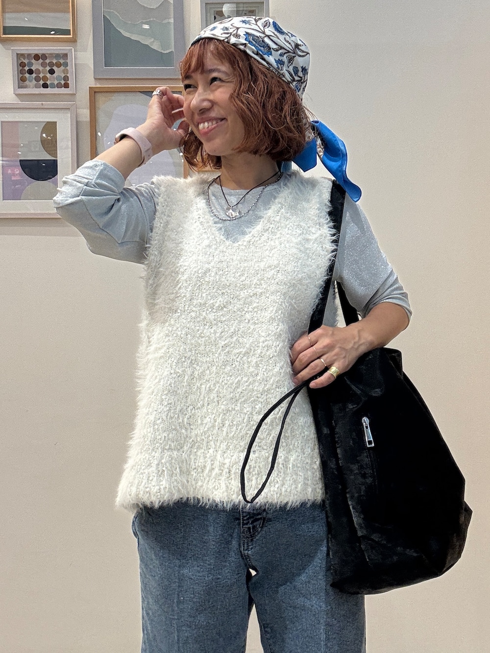 ホワイト系のベスト、ブルー系のデニムパンツ、ブラック系のショルダーバッグを着用したレディースの秋コーディネートの5枚目の写真