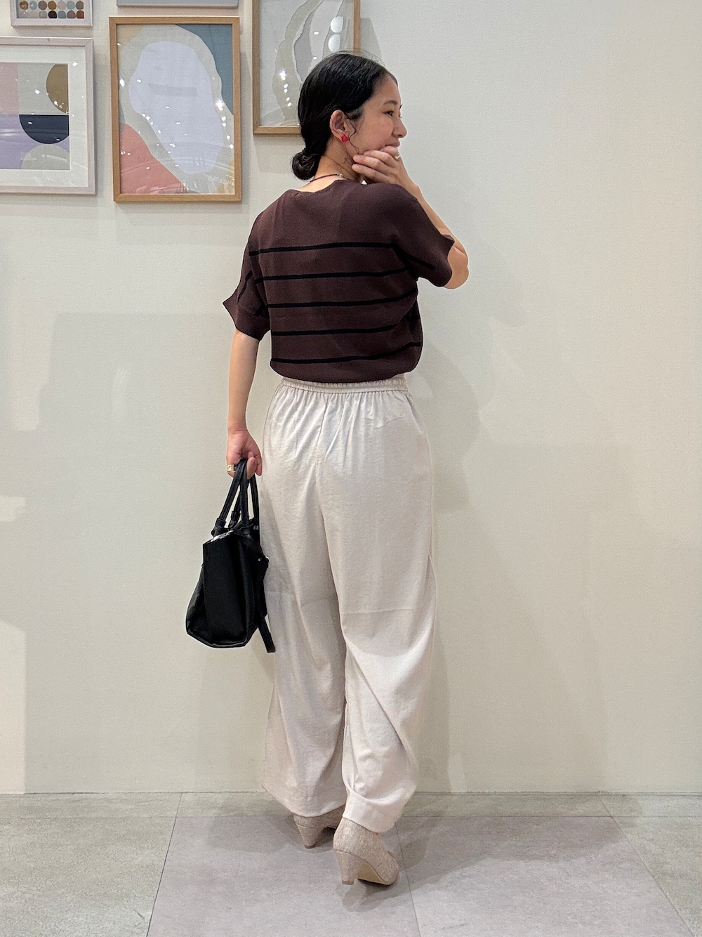 ベージュ系のその他パンツ、ブラック系のトートバッグ、ブラウン系のニット/セーターを着用したレディースの春コーディネートの3枚目の写真