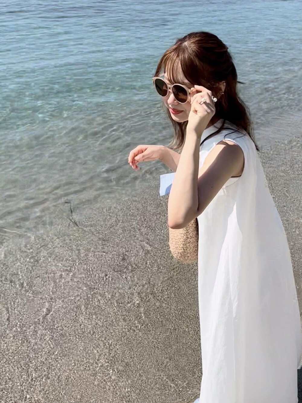 ホワイト系のワンピース、ベージュ系のかごバッグ、ゴールド系のイヤーカフを着用したレディースの夏コーディネートの3枚目の写真