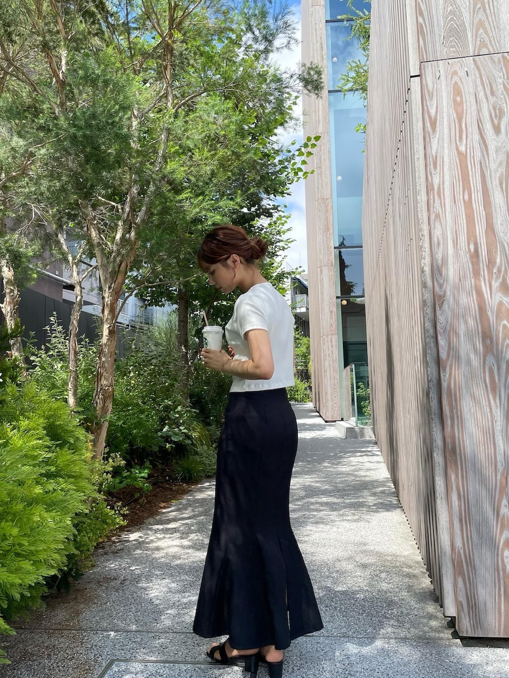 ホワイト系のTシャツ/カットソー、ベージュ系のトートバッグ、ブラック系のサンダルを着用したレディースの夏コーディネートの2枚目の写真