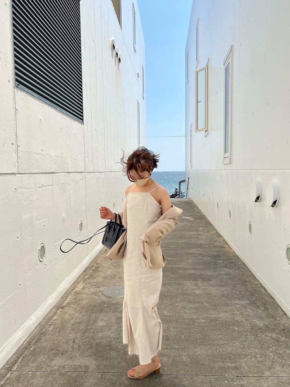 ベージュ系のテーラードジャケット、ホワイト系のワンピース、ベージュ系のサンダルを着用したレディースの夏コーディネートの3枚目の写真