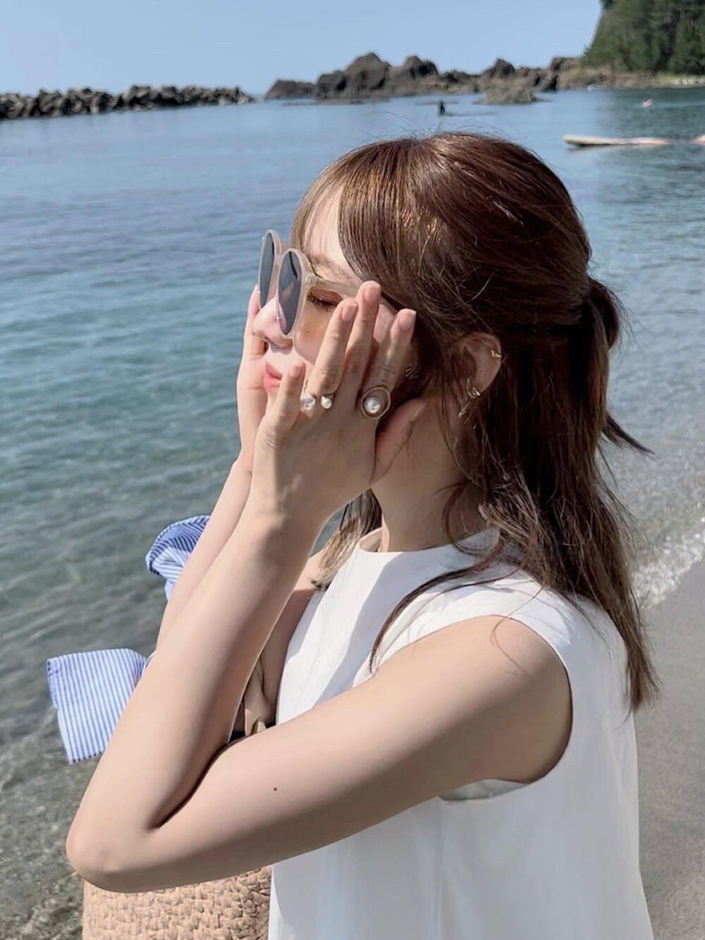 ホワイト系のワンピース、ベージュ系のかごバッグ、ゴールド系のイヤーカフを着用したレディースの夏コーディネートの2枚目の写真