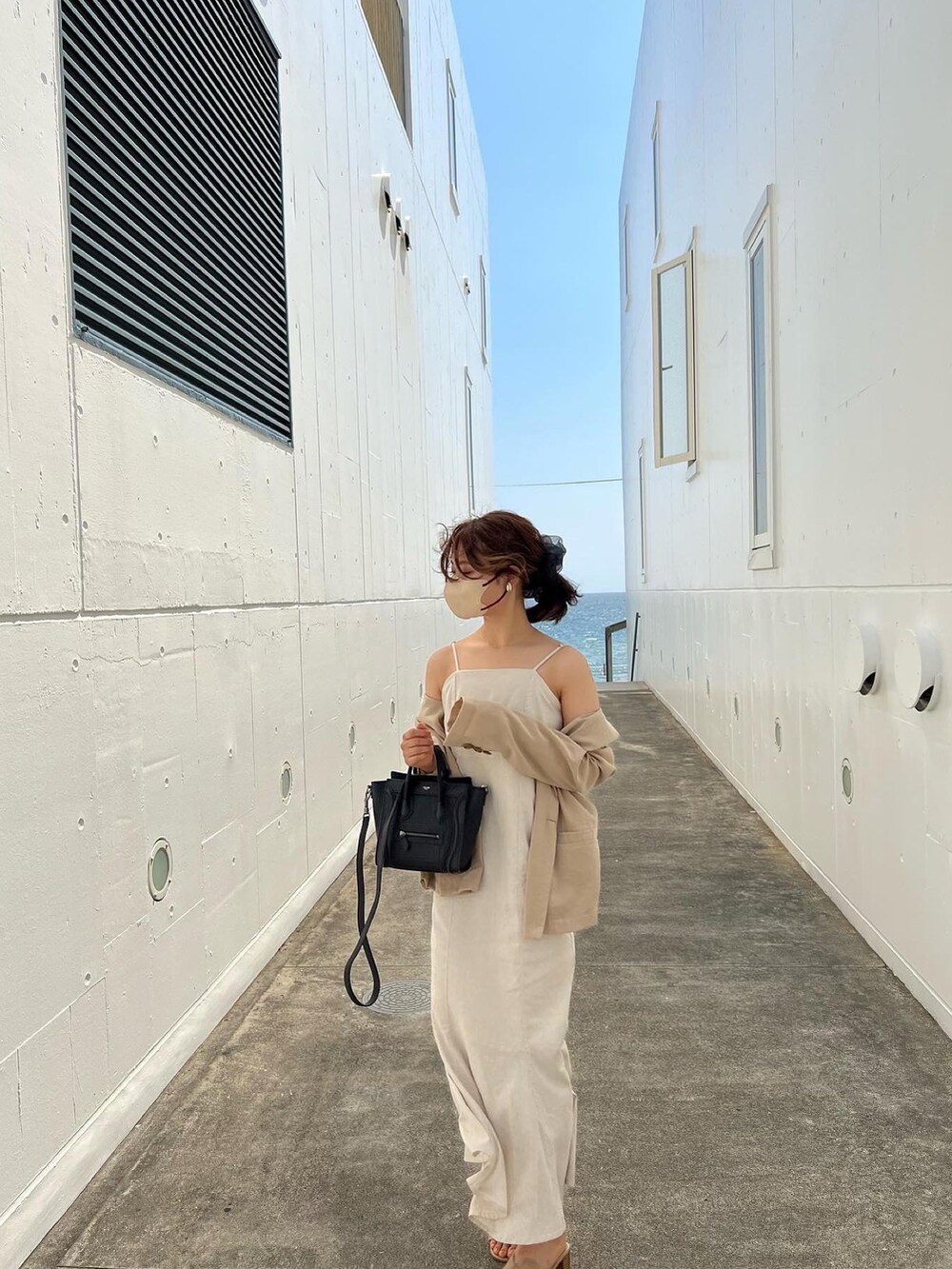 ベージュ系のテーラードジャケット、ホワイト系のワンピース、ベージュ系のサンダルを着用したレディースの夏コーディネートの2枚目の写真