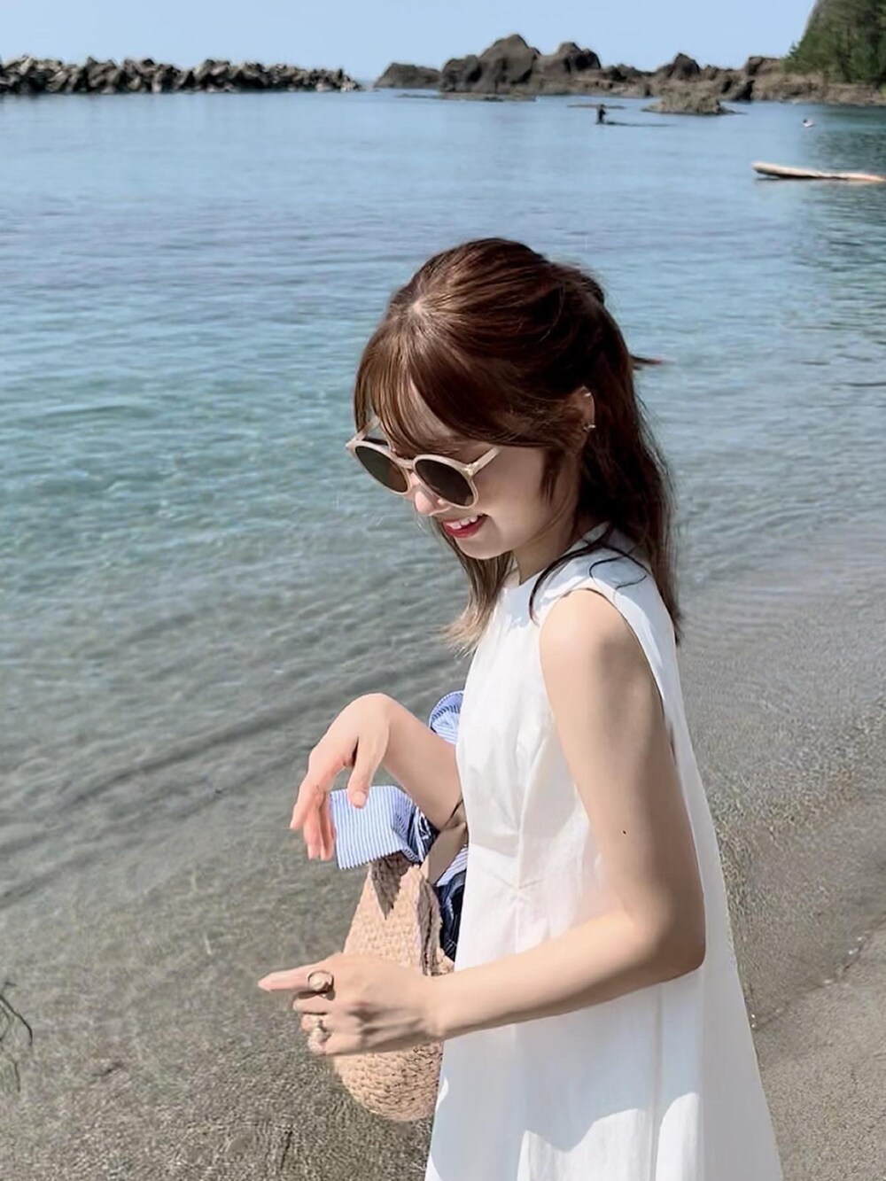 ホワイト系のワンピース、ベージュ系のかごバッグ、ゴールド系のイヤーカフを着用したレディースの夏コーディネートの4枚目の写真