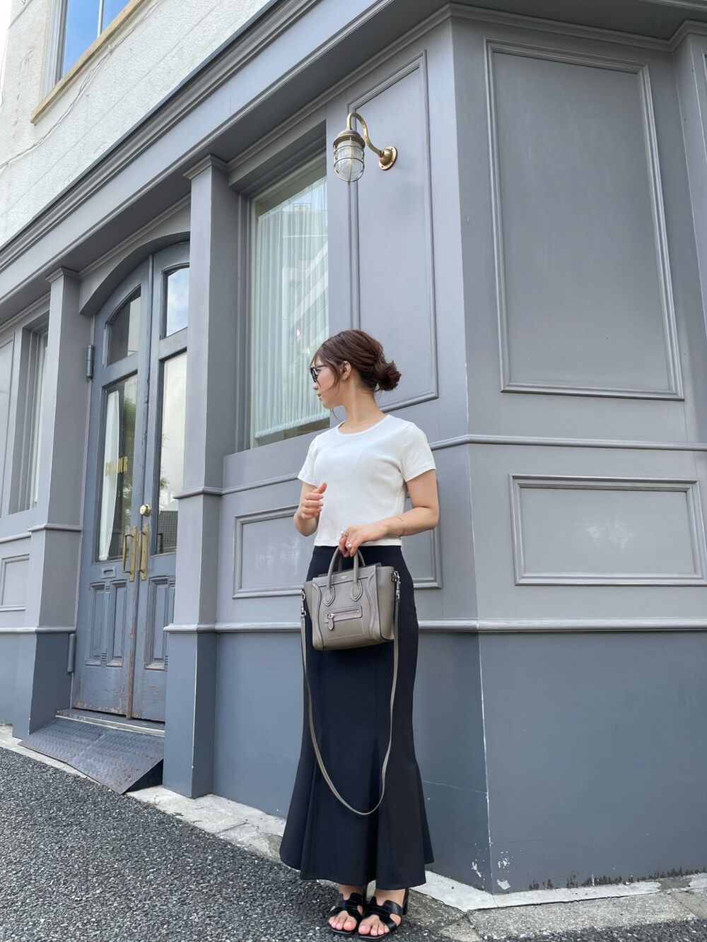 ホワイト系のTシャツ/カットソー、ブラック系のスカート、ブラック系のサンダルを着用したレディースの夏コーディネートの3枚目の写真